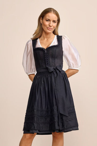 Elegant Verity dirndl in black with tailored cut and 60cm skirt, featuring skirt pockets, front zipper, and subtle apron trim.